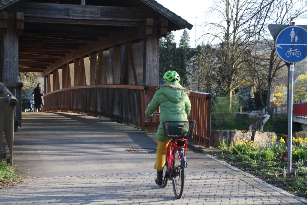 Frau fährt auf Fahrrad über die Struvebrücke in Winterbach.